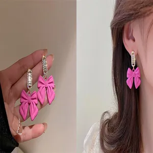 Detailed view of pink bow earrings with sparkling crystal accents shown on model
