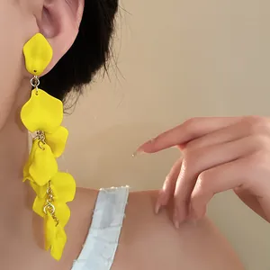 Close-up detail of exaggerated long yellow pleated flower tassel earrings on model