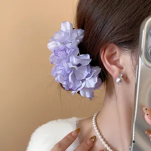 Detailed view of an elegant purple fabric flower hair pin worn on a stylish bun