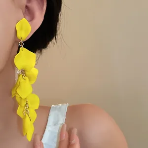 Detail view of yellow ruffled flower tassel clip-on earrings on model's ear