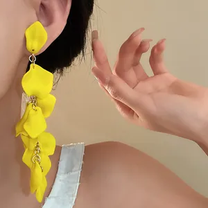 Detailed view of long yellow pleated flower tassel earrings on model's ear