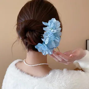 Sweet blue fabric flower hair fork accessory styled on an elegant bun hairstyle