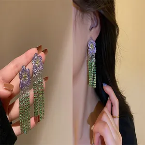 Exquisite detailed view of floral earrings with long green crystal tassels worn on ear