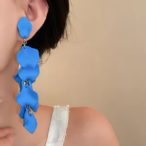 Macro detail of blue matte wrinkled flower petal tassel earrings on an Asian model