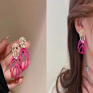 Detailed close-up showing fuchsia and gold layered hollow leaf earrings worn by a model