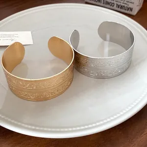 Elegante offene Vintage-Metallarmreifen mit Blumenprägung auf einem weißen Keramikteller
