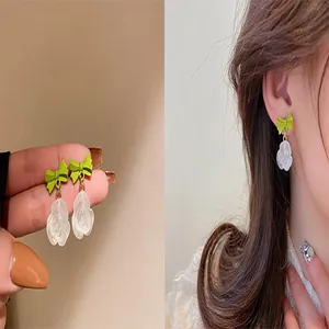 Elegant lime green bow and frosted white rose flower drop earrings on model for detailed view