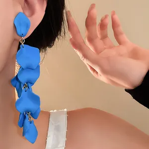 Detail shot of long electric blue floral petal tassel ear clips on a model's ear.