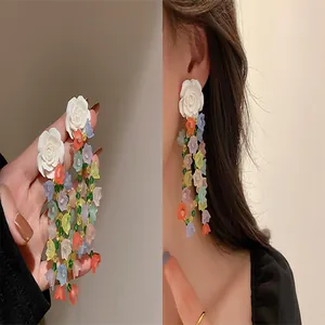 Close-up detail of elegant colorful floral tassel earrings with large white rose studs