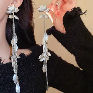 Primo piano dettagliato di orecchini a nappa lunghi con fiori e foglie d'argento