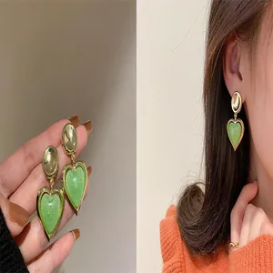 Close-up and model wearing elegant light green heart drop earrings with gold finish