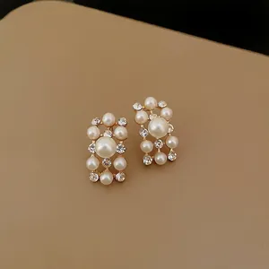 Primo piano di eleganti orecchini d'oro vintage con perle e strass di varie dimensioni e lucentezza