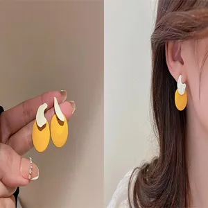 Unique asymmetric yellow and white geometric earrings with silver needles detail view