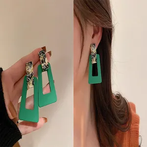 Stylish green rectangular drop earrings shown on a female model for fashion detail.