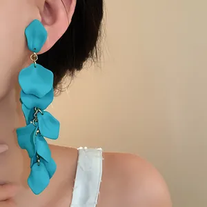 Close-up detail of long pleated turquoise flower petal tassel earrings worn by model