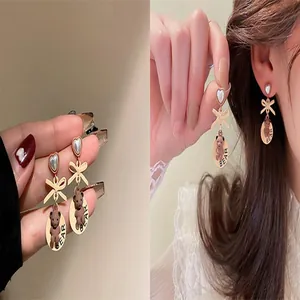 Detailed view of cute teddy bear drop earrings featuring heart pearls and golden bows