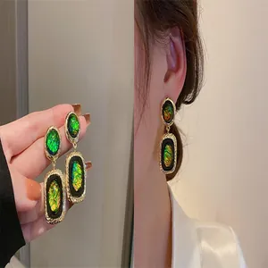 Detail of vintage gold-tone earrings with iridescent green and yellow inlay inserts