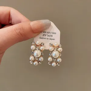 Primo piano di eleganti orecchini geometrici dorati con perle e strass scintillanti.