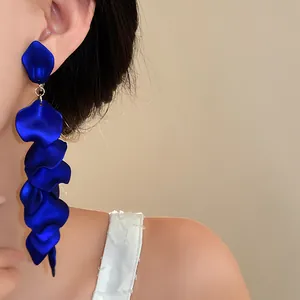 Close-up view of elegant cobalt blue wrinkled petal tassel clip-on earrings worn by a model