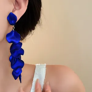 Detail of long royal blue flower petal tassel ear clips worn by a model.