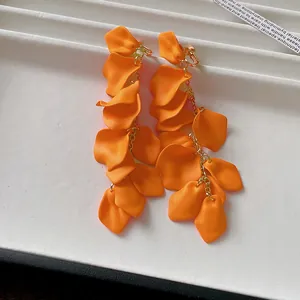 Close-up of vibrant orange pleated flower petal tassel clip-on earrings for women