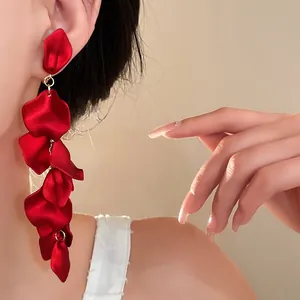 Detailed view of elegant long red floral petal tassel earrings worn by a fashion model