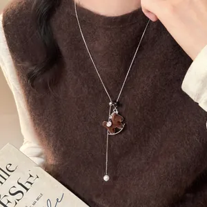 Elegant flocked rocking horse pendant necklace on brown sweater for autumn and winter