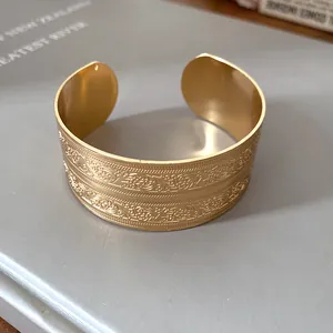 Nahaufnahme antiker Prägemuster auf einem breiten goldenen offenen Metallarmreif