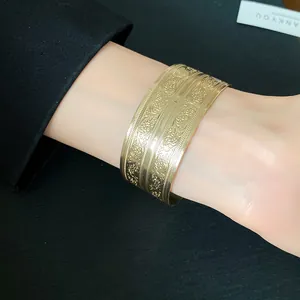 Detailansicht eines goldenen Manschettenarmbands mit geprägten floralen Mustern.