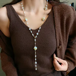 Close-up of elegant French style irregular pearl Y-necklace on brown sweater