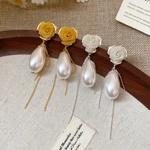 Dettaglio di orecchini a rosa in rete vintage con perla e nappe a catena lunga.