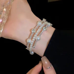 Elegant multi-layer pearl bracelet with sparkling rhinestones worn on a model's wrist
