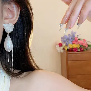 Primo piano di eleganti orecchini a perla rosa con delicate nappe in catena argento