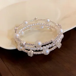 Elegant multi-layered bracelet featuring white pearls and sparkling crystals on silver