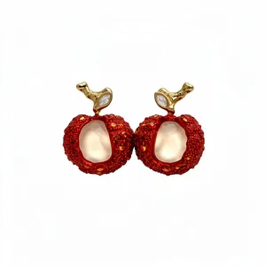 Elegant red lychee fruit drop earrings with zircon and resin details on white background