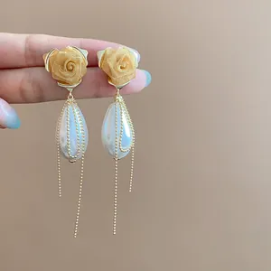 Dettaglio di orecchini a rosa in rete vintage con perle a goccia e nappe dorate