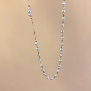 Close-up of elegant French style sweater necklace with white pearls and gold chain.