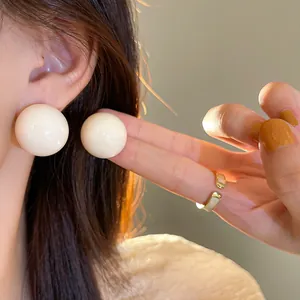 Dettaglio ravvicinato di eleganti grandi orecchini a sfera bianco crema su una modella