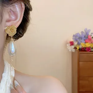 Dettaglio dell'orecchino a rosa vintage con elegante goccia di perla e nappe d'oro