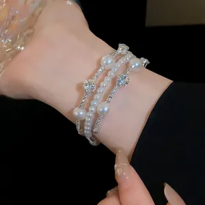 Elegant multi-layer pearl and rhinestone bracelet detail on a woman's slender wrist