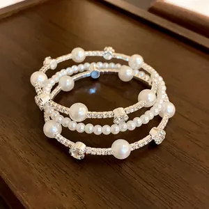 Detailed view of French luxury multi-layer pearl and rhinestone bracelet on wood.
