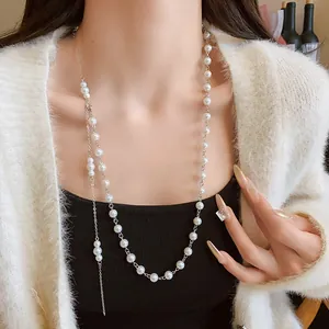 Elegant long pearl necklace for women, worn as a sweater chain over a white cardigan