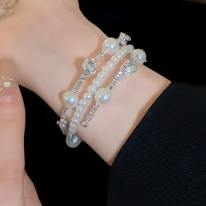 Close-up of elegant three-layer bracelet featuring lustrous pearls and sparkling rhinestones