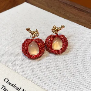 Detail view of handcrafted red resin lychee earrings featuring elegant gold zircon stems
