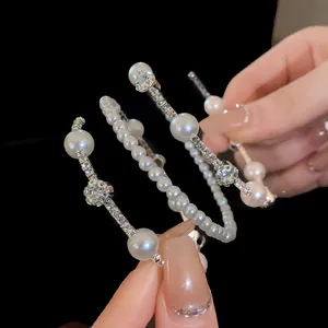 Macro view of elegant French style pearl and rhinestone layered bracelets on hand