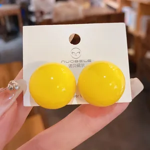 Primo piano di orecchini a sfera gialli con aghi in argento S925 su cartoncino