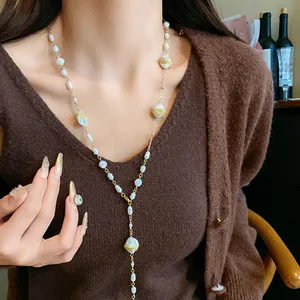 Close-up of elegant Y-shaped sweater chain with irregular pearls on a brown knit cardigan
