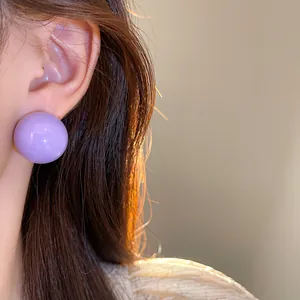 Dettaglio ravvicinato di un grande orecchino a sfera viola indossato sull'orecchio