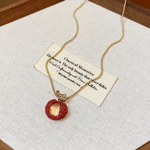 Detailed macro shot of a red resin lychee pendant necklace with elegant gold zircon accents