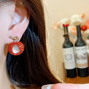Exquisite close-up detail of red lychee-shaped resin earring with zircon accents